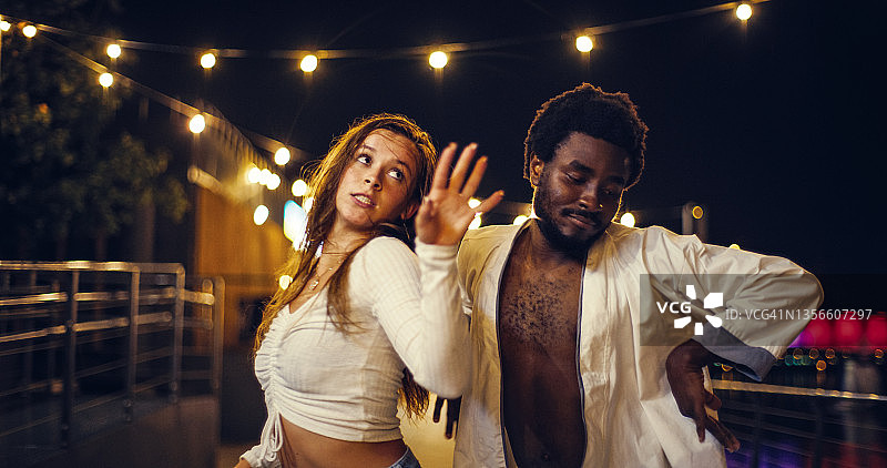 年轻、多元化的情侣在潮湿的城市街道上表演现代快节奏的舞蹈。玩得开心，微笑，做疯狂的姿势图片素材