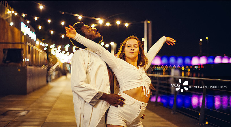 在潮湿的城市街道上跳现代舞的年轻情侣图片素材