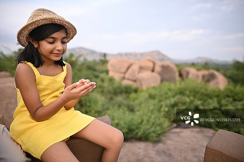 女孩坐在被巨石环绕的石头上图片素材