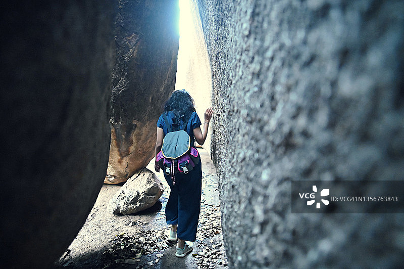 穿过巨石之间狭窄通道徒步的女人图片素材
