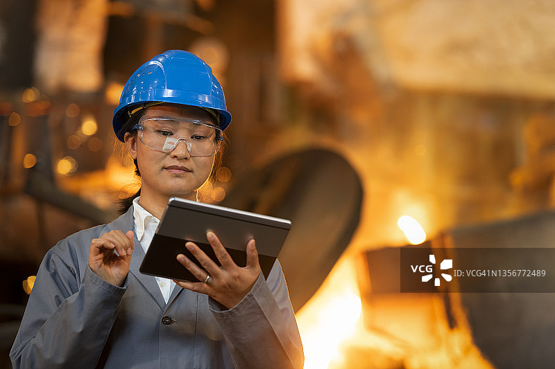 中年妇女在铸造厂使用平板电脑图片素材