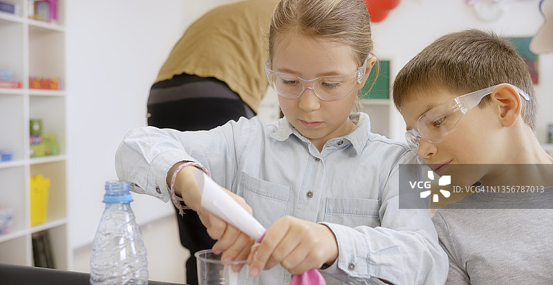 在教室里，女孩为科学实验气球充气图片素材