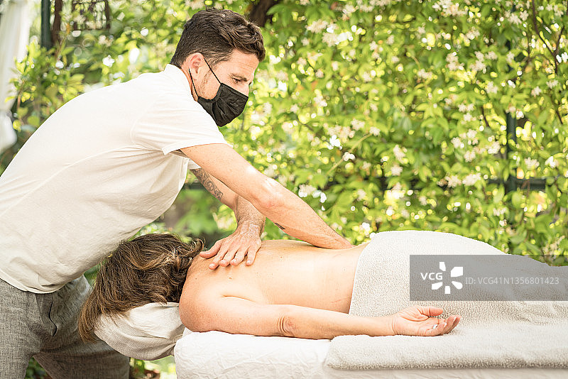 在户外以花帘为背景工作的按摩师图片素材