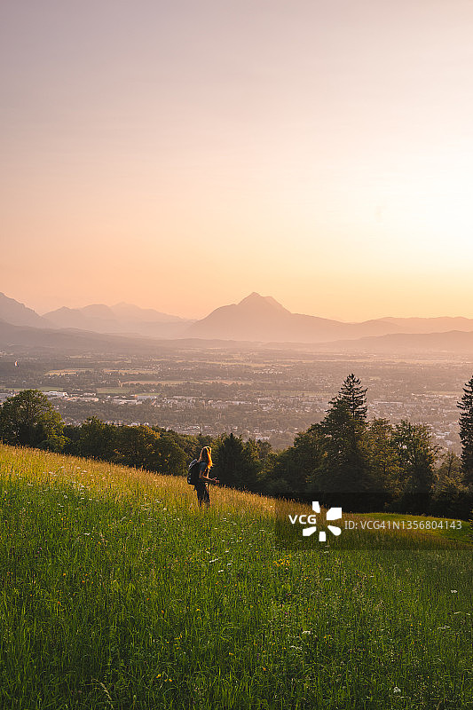 女徒步者在长满草的山脊上放松图片素材