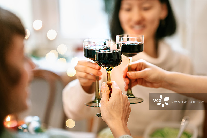 朋友们享用圣诞晚餐，品尝葡萄酒图片素材