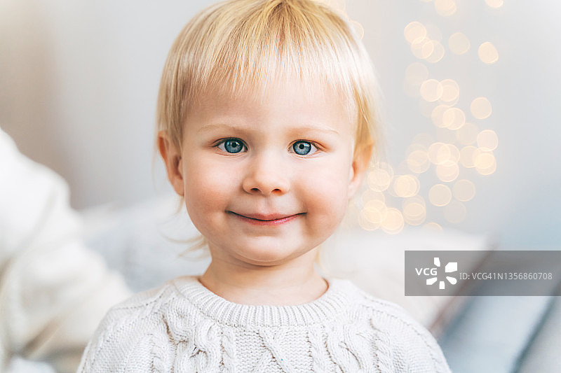 身穿粉色圣诞毛衣的可爱宝宝等待节日礼物图片素材