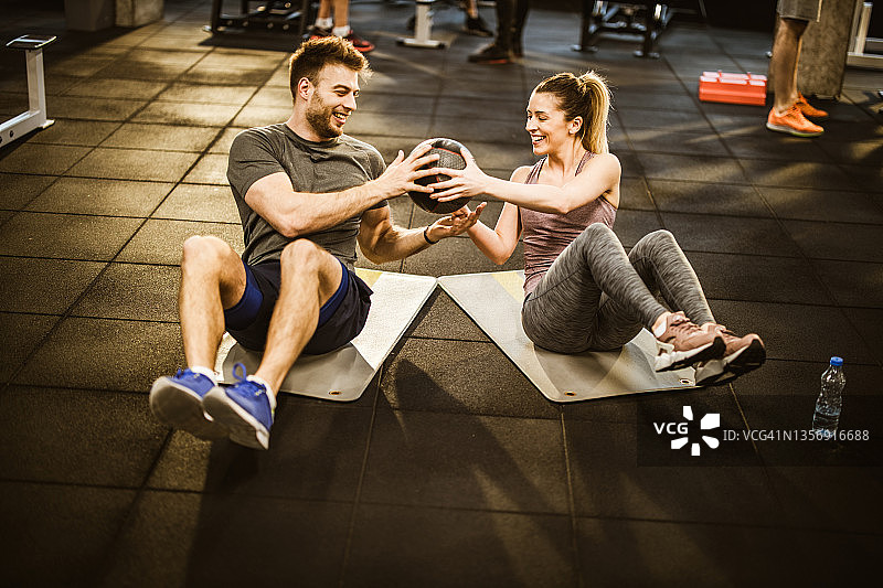 快乐的运动情侣在健身房合作进行药球训练图片素材