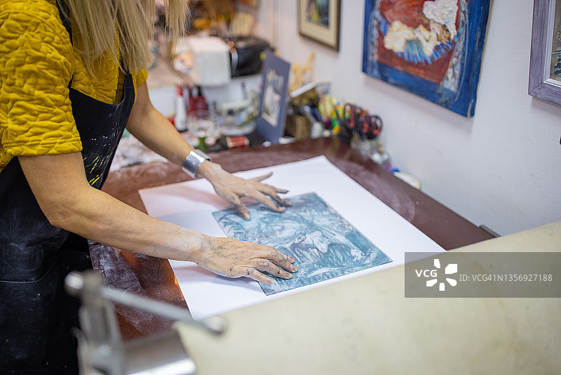 女性艺术家调整纸上的雕刻印记图片素材