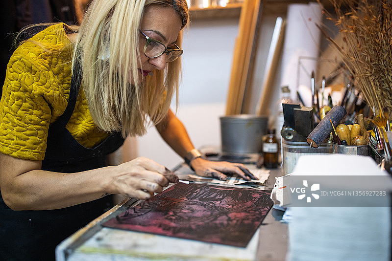 女艺术家用棉签清洁雕刻印记上的墨水图片素材