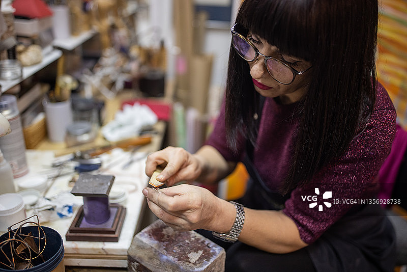 熟练的白人女性工匠用砂纸打磨戒指图片素材