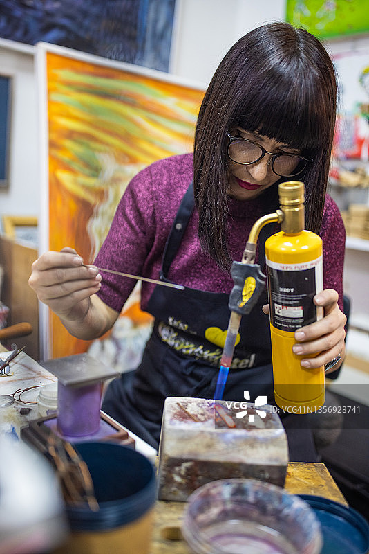 专注创作的女艺术家，加热金属以便塑形图片素材