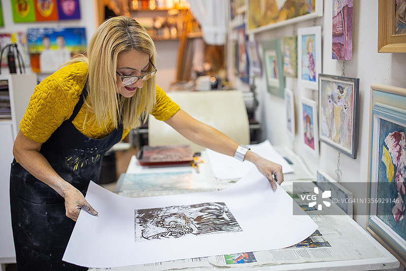 自豪的白人女艺术家在欣赏她创作的石版画艺术品图片素材