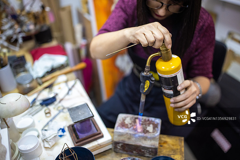 无法辨认的女珠宝商用喷枪加热金属图片素材