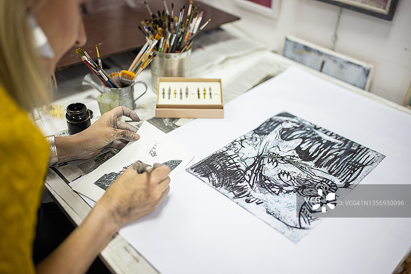 用钢笔在纸上绘画的匿名女子图片素材