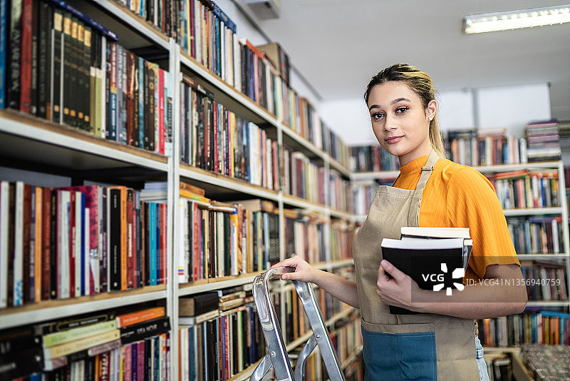 书商在书架上整理书籍的肖像图片素材