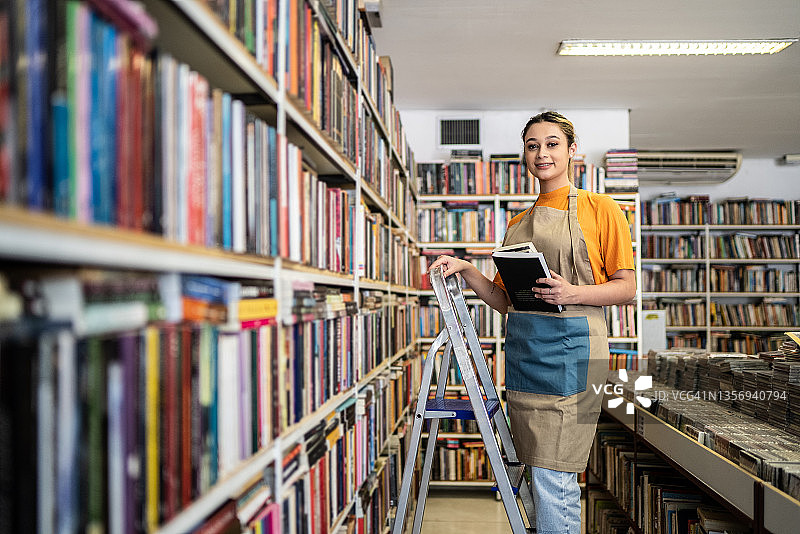 书商在书架上整理书籍的肖像图片素材