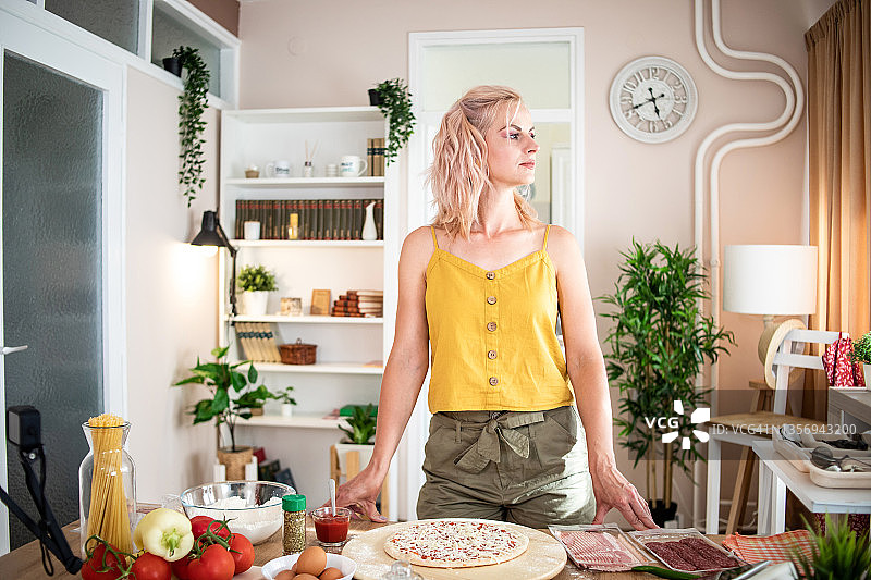 年轻女人在家准备披萨，参考在线食谱图片素材