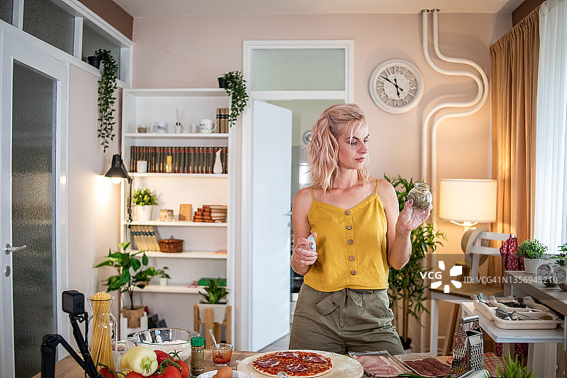 年轻女人在家准备披萨，参考在线食谱图片素材