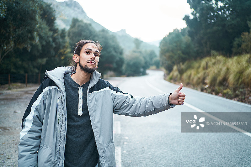 男子在山区公路搭便车图片素材