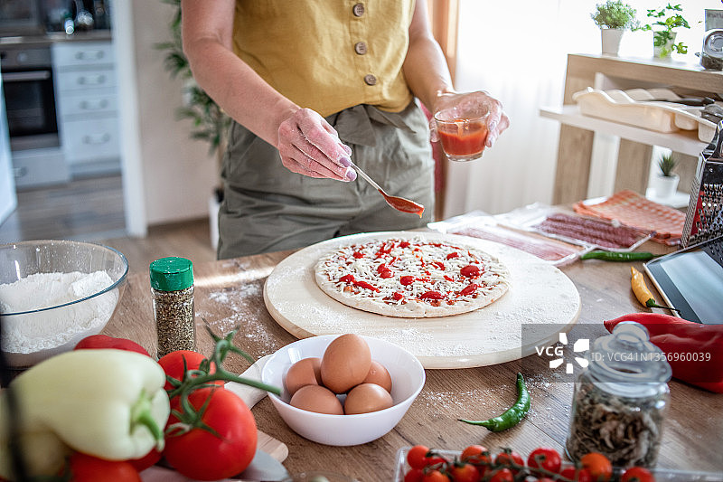 年轻女人在家准备披萨，参考在线食谱图片素材
