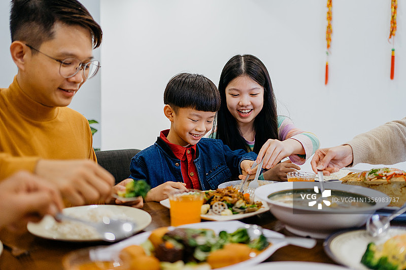 年轻的兄弟姐妹在家吃中国新年团圆饭图片素材
