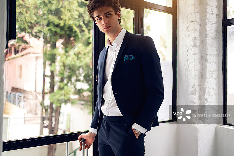 穿着西装，双手插在口袋里的优雅年轻白人男子图片素材