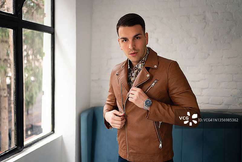 身穿棕色皮夹克的自信时尚的年轻男人图片素材