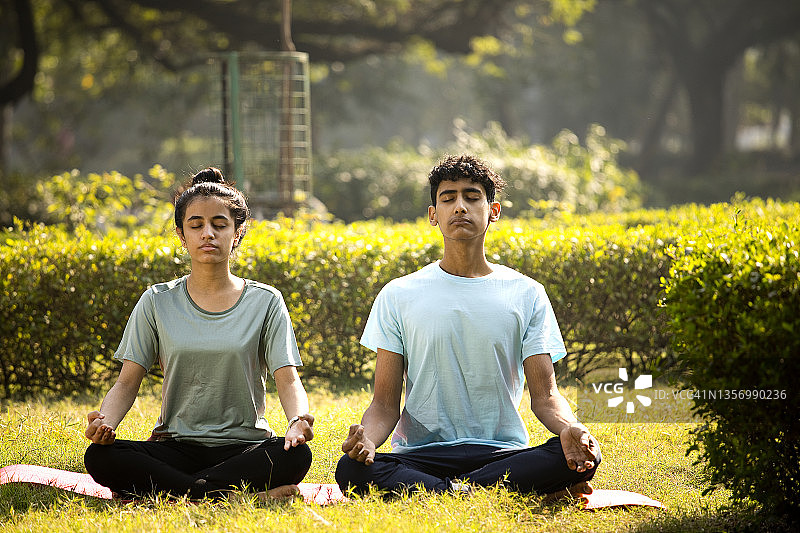在公园冥想的青少年男孩和女孩图片素材