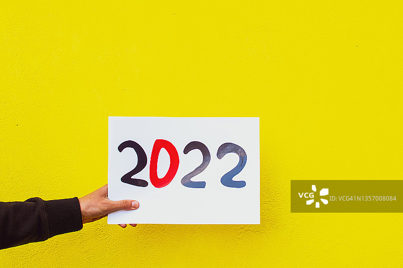 人手拿着黄色背景的2022年标志图片素材
