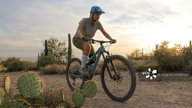 骑山地自行车的女人在沙漠中骑行图片素材