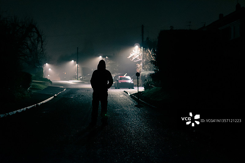 雾夜郊区街道上的恐怖兜帽人概念图图片素材