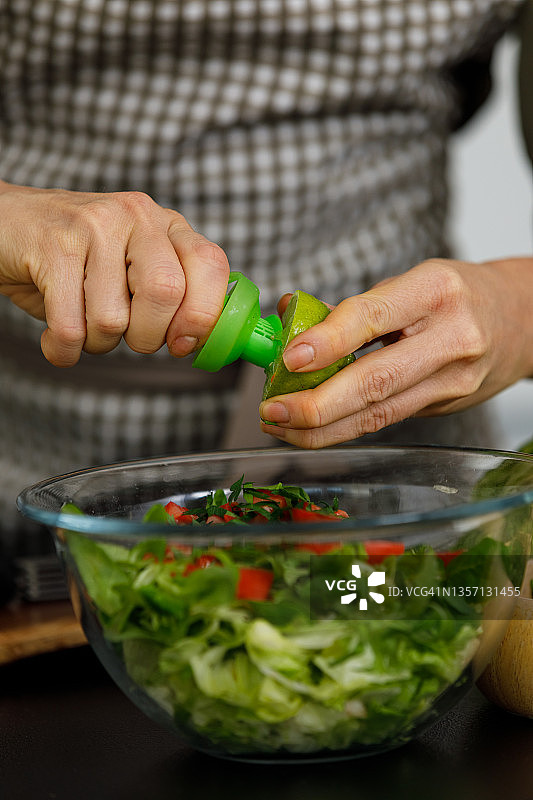女人将柑橘喷雾器放入酸橙中，然后将其用于她准备的沙拉图片素材