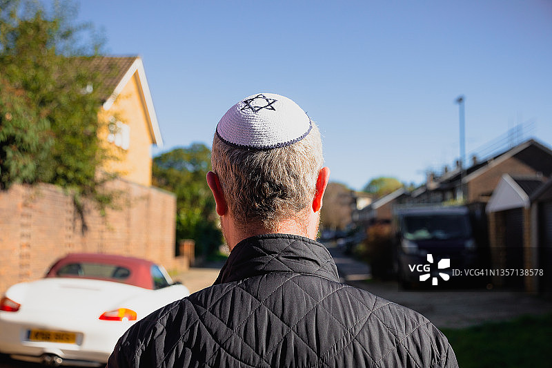 一名戴着小圆帽的犹太人走在居民区街道上图片素材