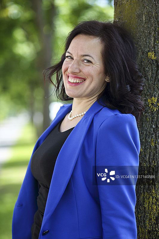 快乐的女人靠在树干上休息图片素材