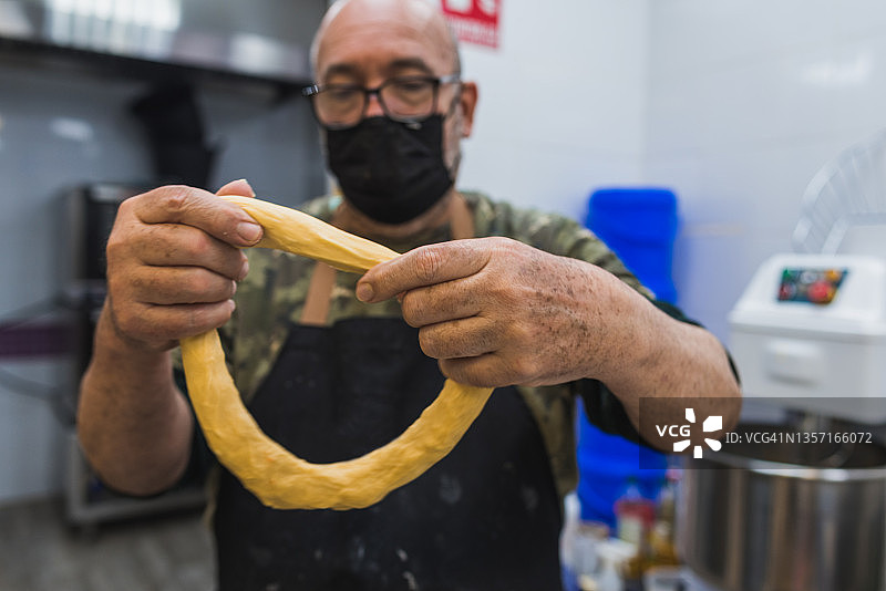 糕点师傅在糕点店内拉伸国王面包面团图片素材
