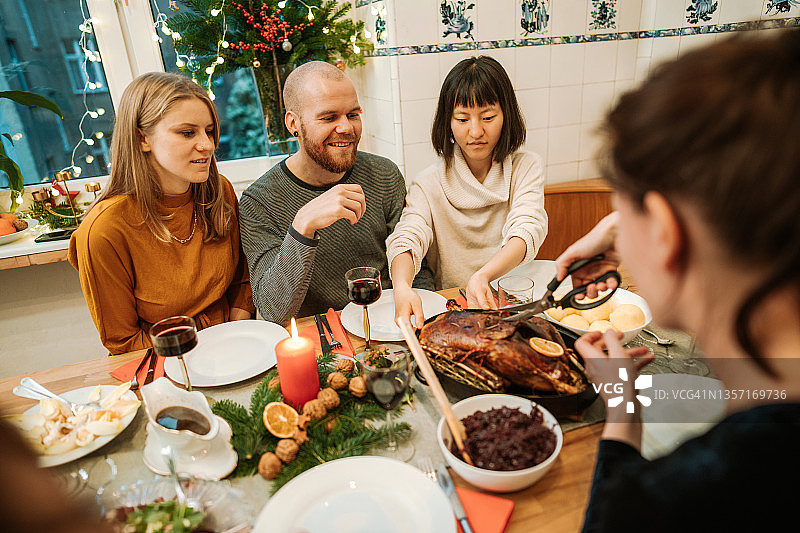 感恩节晚餐时，女人在餐桌上为家人提供酿火鸡图片素材
