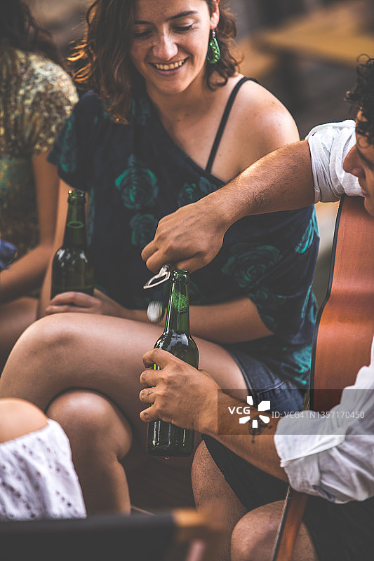 年轻男人打开一瓶啤酒与朋友分享图片素材