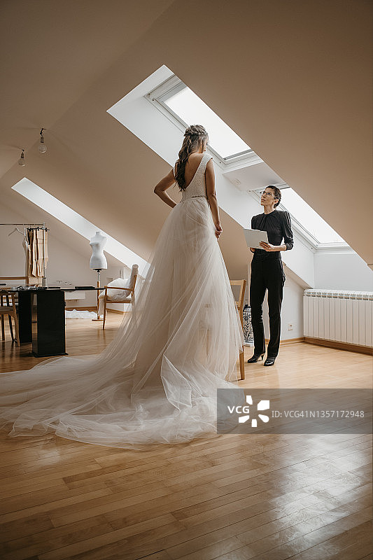 年轻女人在婚纱店和裁缝一起试穿婚纱图片素材