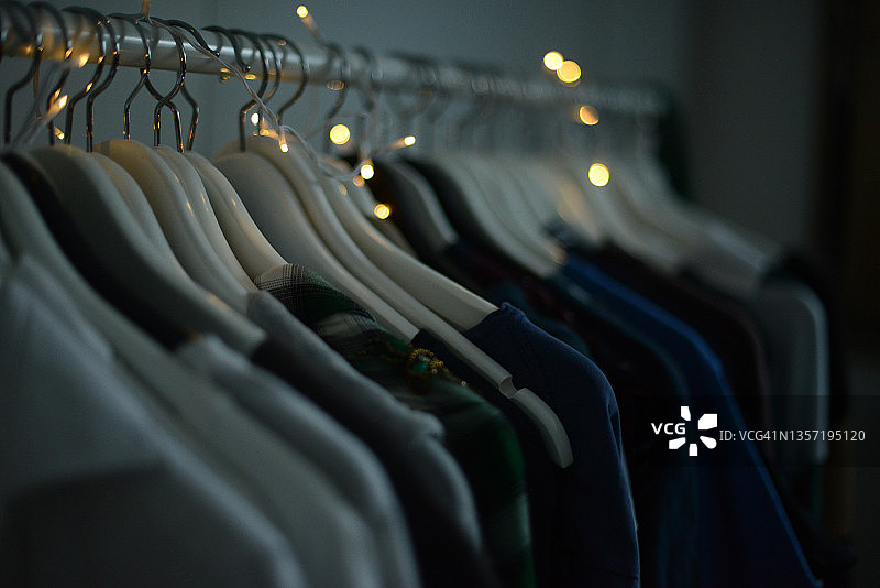 衣架上挂着一排衣服，用小圣诞灯装饰图片素材