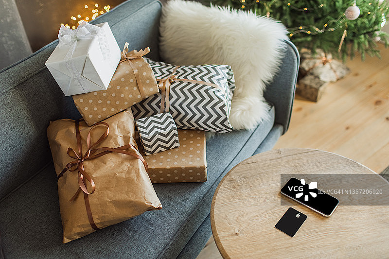 蓝色沙发，礼品，带智能手机和信用卡的桌子，用于圣诞节在线购物图片素材