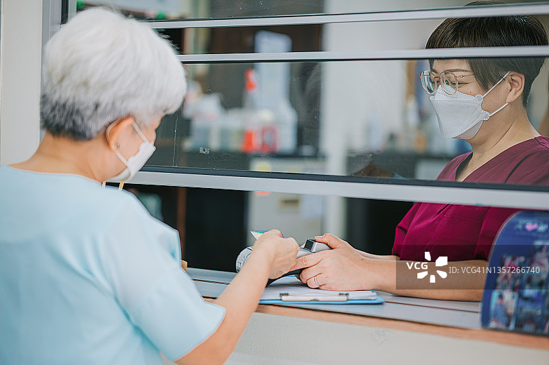中国老年妇女在诊所用信用卡支付医疗费用图片素材