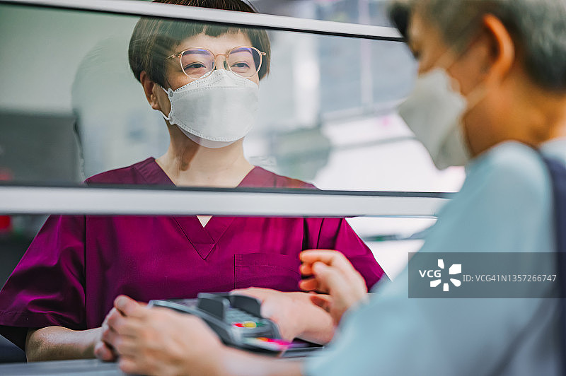 中国老年妇女在诊所用信用卡支付医疗费用图片素材