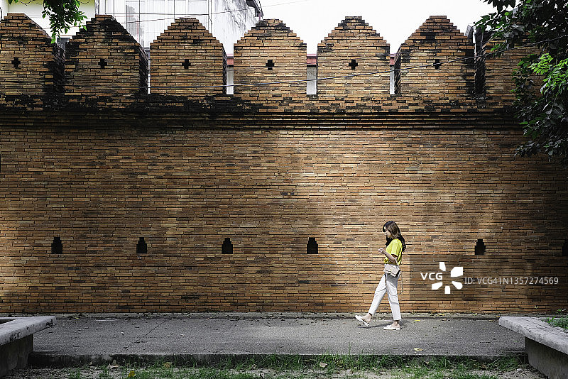 亚洲女游客走在泰国清迈塔佩门砖墙旁图片素材