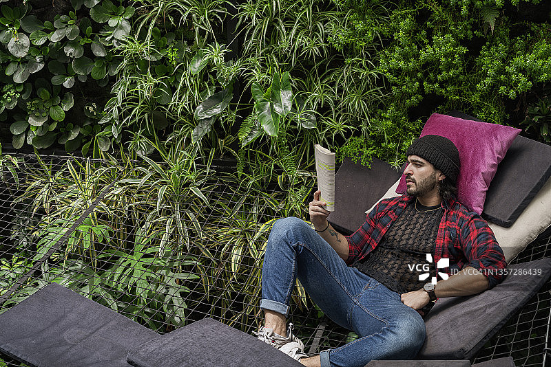 男人坐在办公室的吊网上休息和阅读图片素材