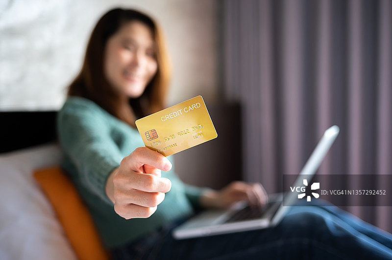 女人用笔记本电脑在线购物，手持信用卡特写图片素材