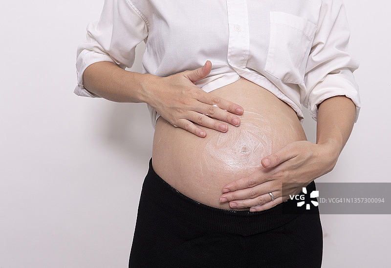 快乐孕妇在孕肚上涂抹护肤乳液，预防妊娠纹，呵护健康肌肤图片素材