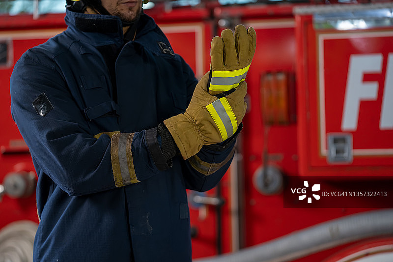 消防员身穿安全头盔和制服站在消防车旁，配备消防设备图片素材