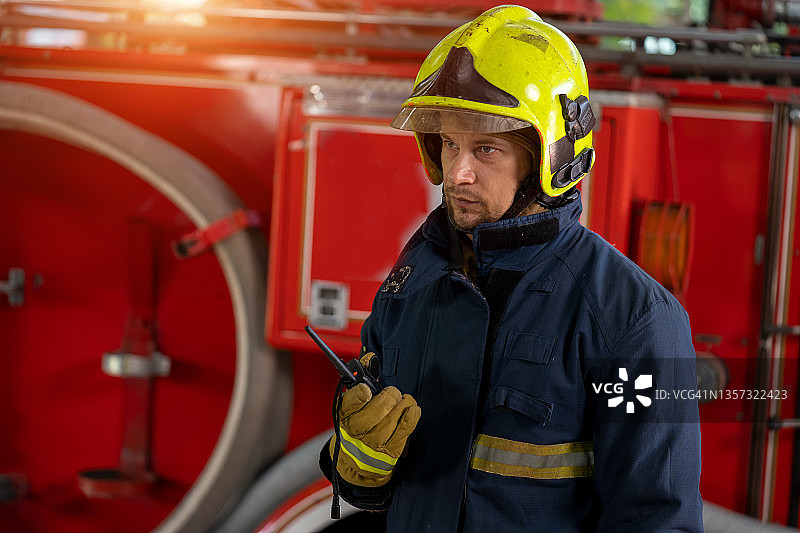 身穿防护服的消防员站在消防车旁，用无线电交谈图片素材