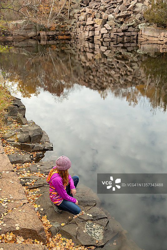 秋天，在废弃采石场池塘边的女孩图片素材