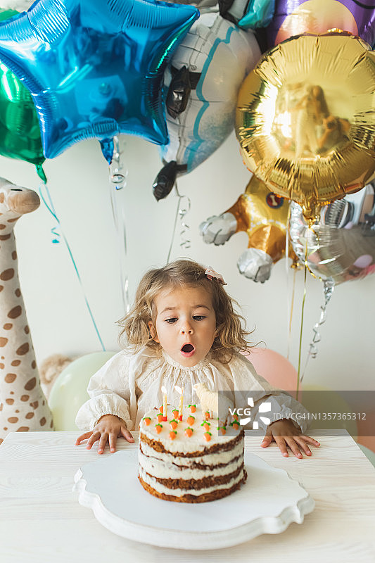 年轻女孩吹灭蜡烛庆祝2岁生日图片素材